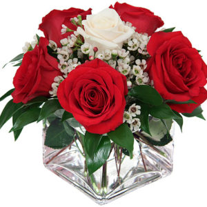 composizione con rose rosse e una rosa bianca al centro